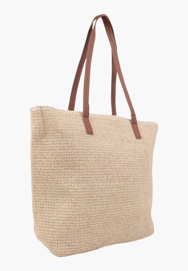 Z boku beżowej torebki damskiej shopper z długimi uchwytami na białym tle
