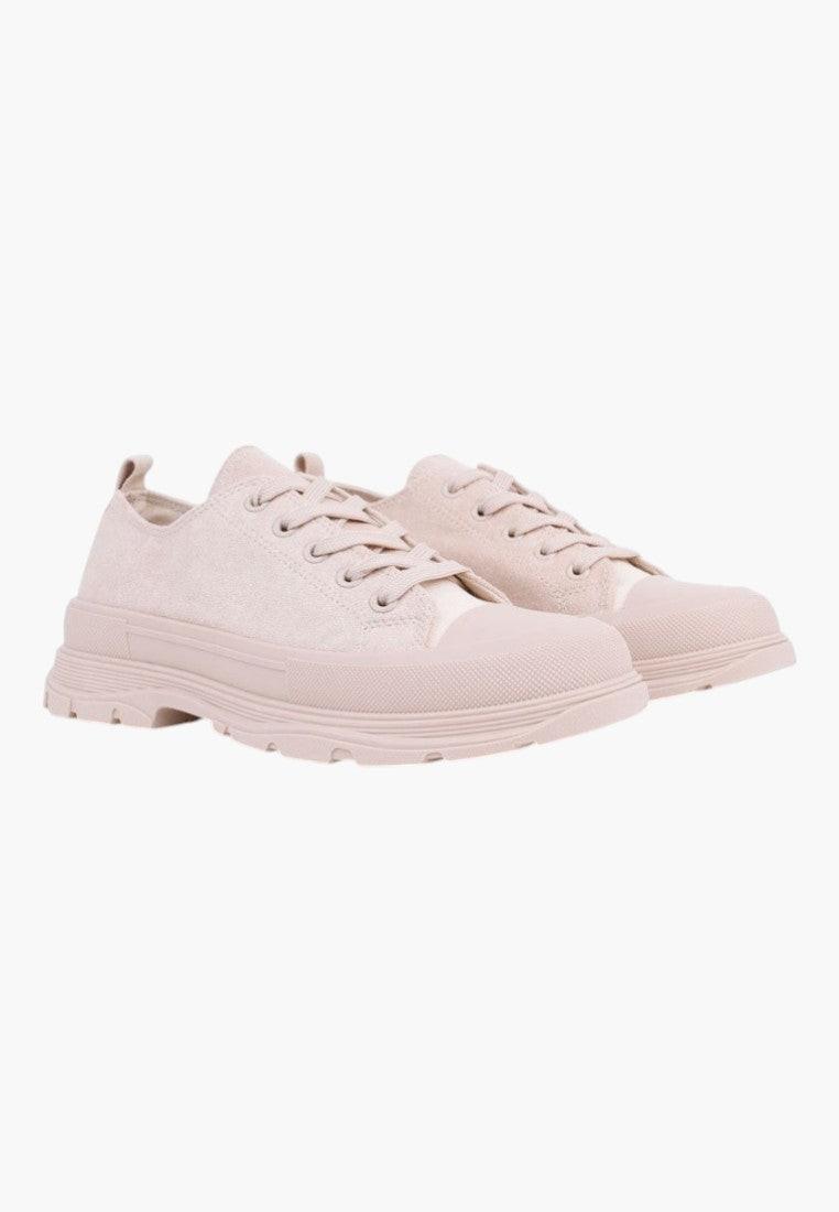 Side view of beige lace-up sneakers featuring a rounded toe on a white background