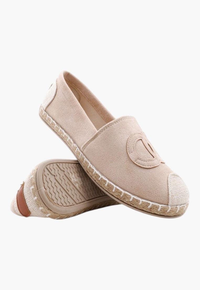 Close-up detail of beige slip-on shoes showing textured surface and rounded toe