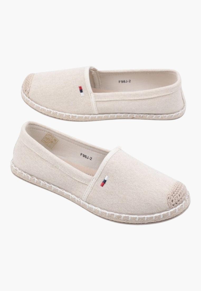 Lifestyle view of beige slip-on shoes with elastic sides on a white background