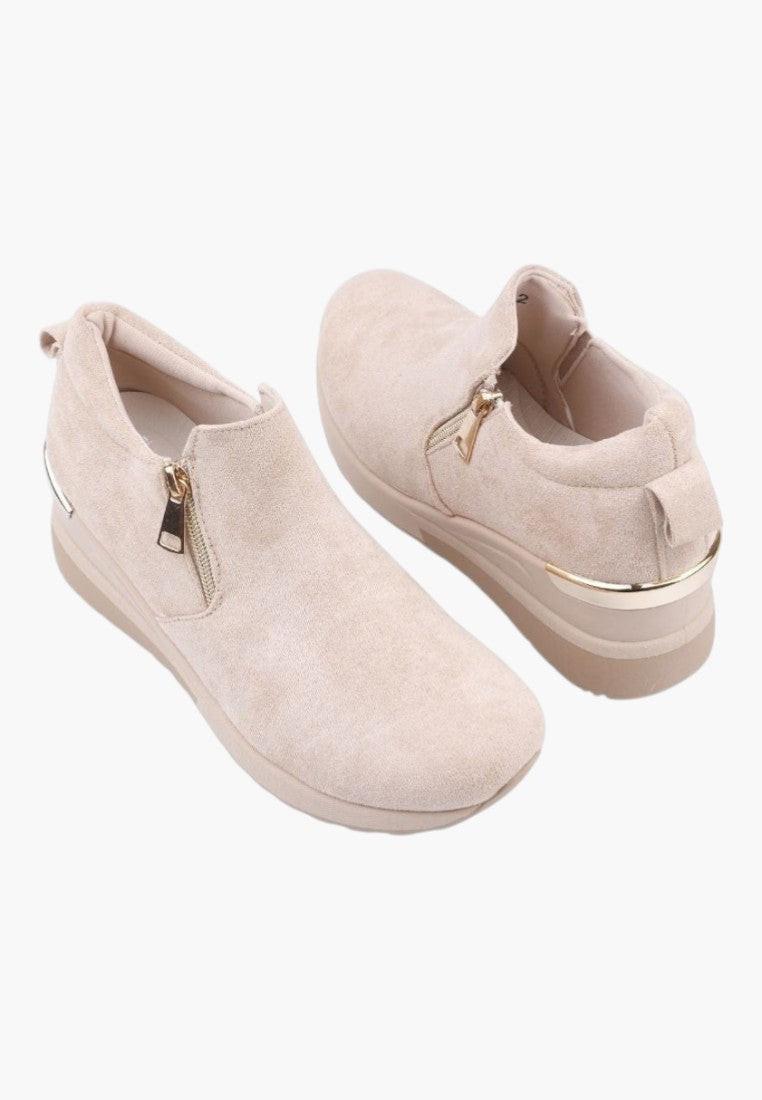 Zbliżenie na materiał ekozamszowy beżowych sneakersów damskich.