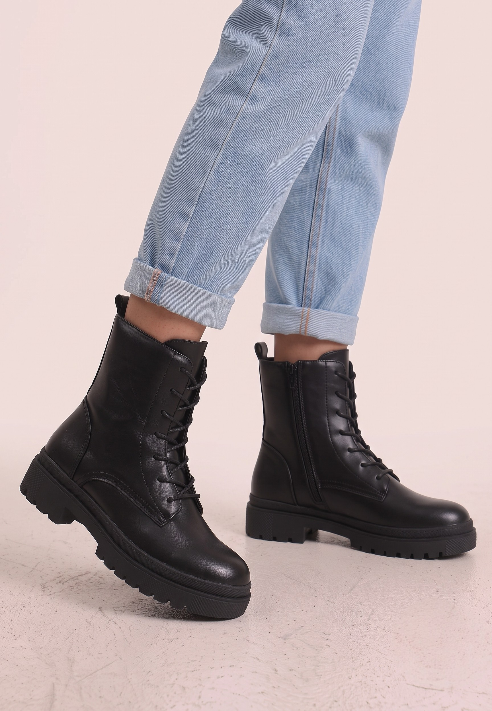 Falio black faux leather ankle boots with lace-up closure and chunky soles worn with light blue jeans