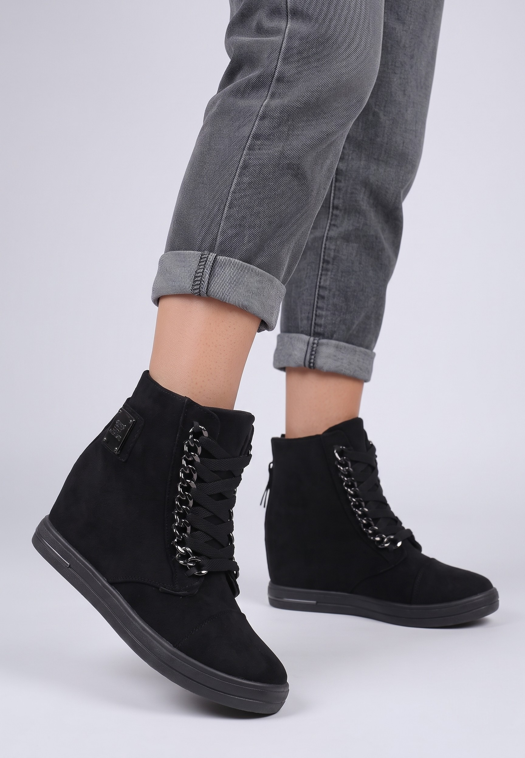 Falio black faux suede wedge sneakers with silver chain detail and lace-up closure worn with grey jeans