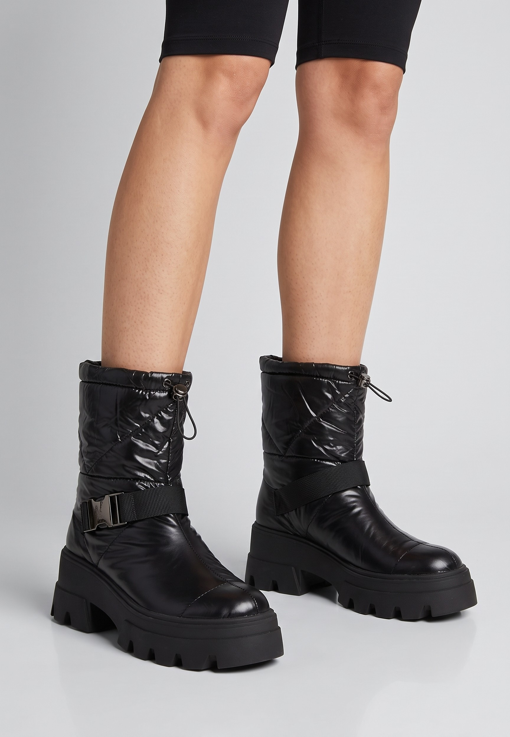 Falio black quilted textile ankle snow boots with a thick lug sole, decorative ankle strap, and drawstring top.