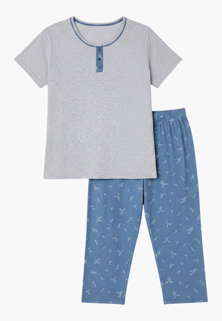 Falio women's plus size two-piece pajama set. Grey short-sleeve top with blue button detail and blue capri pants with a white abstract pattern. 100% cotton.