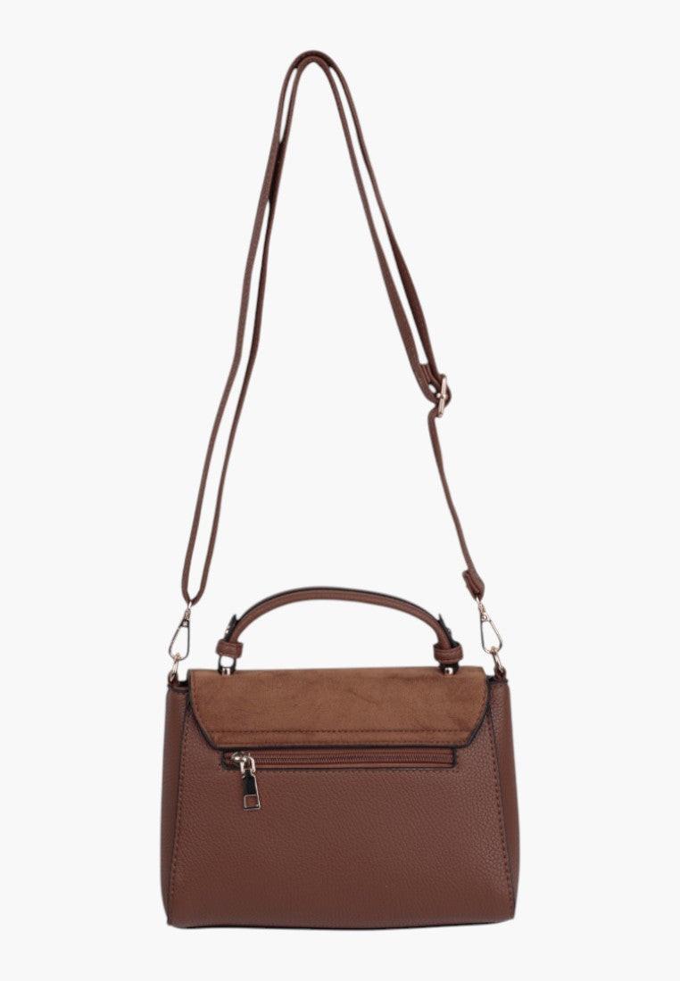 Side view of the brown handbag featuring an adjustable strap and silver hardware against a white background.