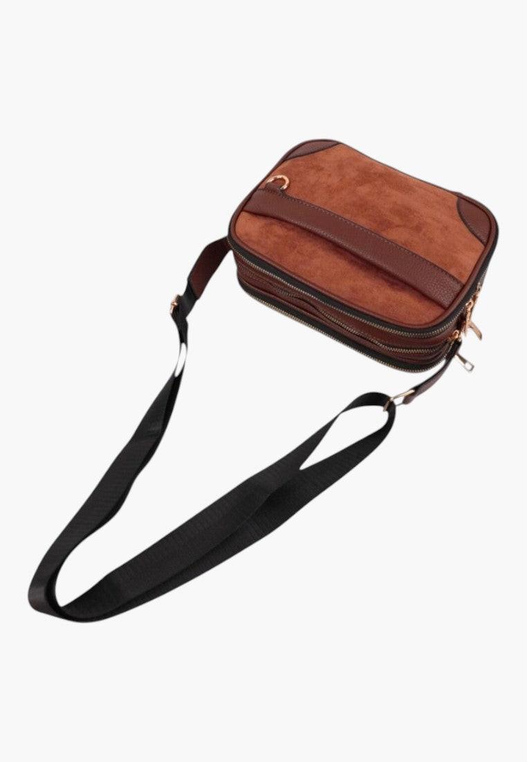 Side view of the brown shoulder bag featuring an adjustable strap and zipper closure.