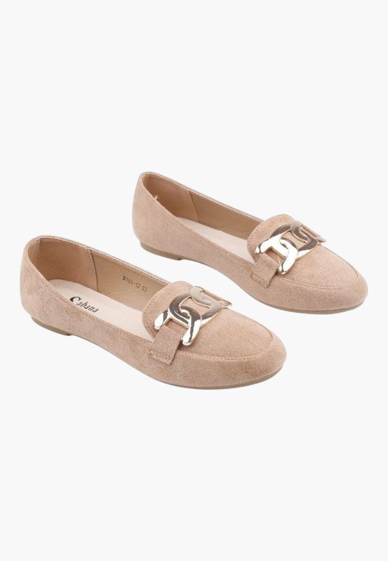 Lifestyle shot of beige suede loafers with a flat sole and decorative buckle.