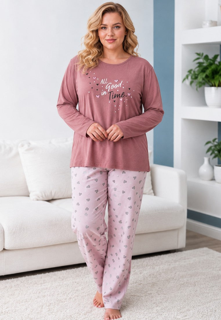 Lifestyle shot of plus size cotton pajama set featuring long sleeves and heart-patterned trousers in pink tones.