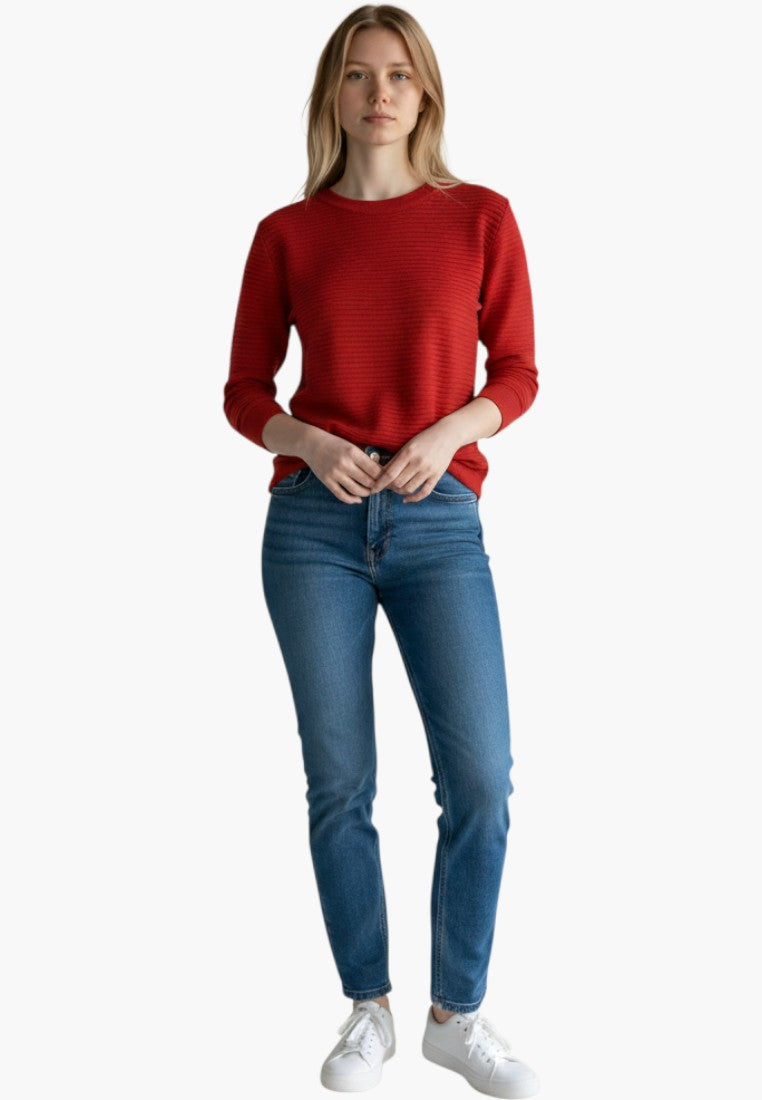 Modelka w czerwonym swetrze z długim rękawem i okrągłym dekoltem, stylizacja casualowa.