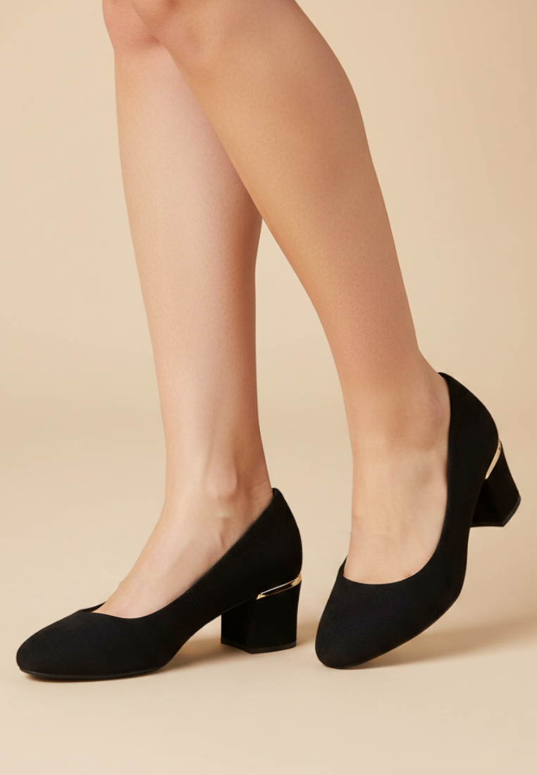 Falio black faux leather block heel pumps with a 5 cm heel and round toe worn by a model on a beige background