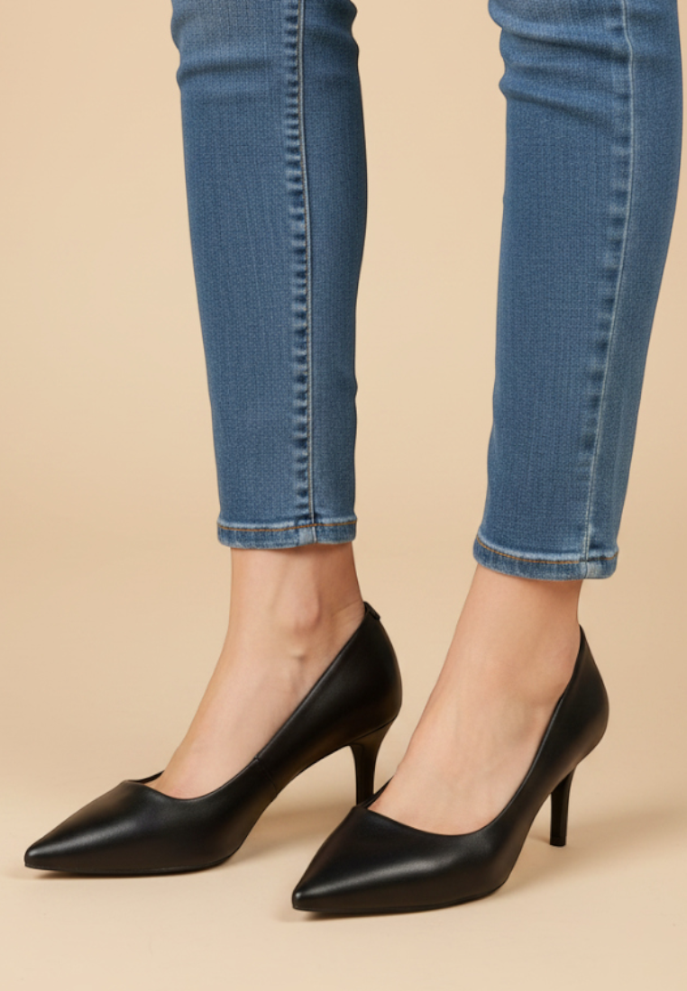 Falio black faux leather pointed toe stiletto pumps worn with blue skinny jeans on a neutral background