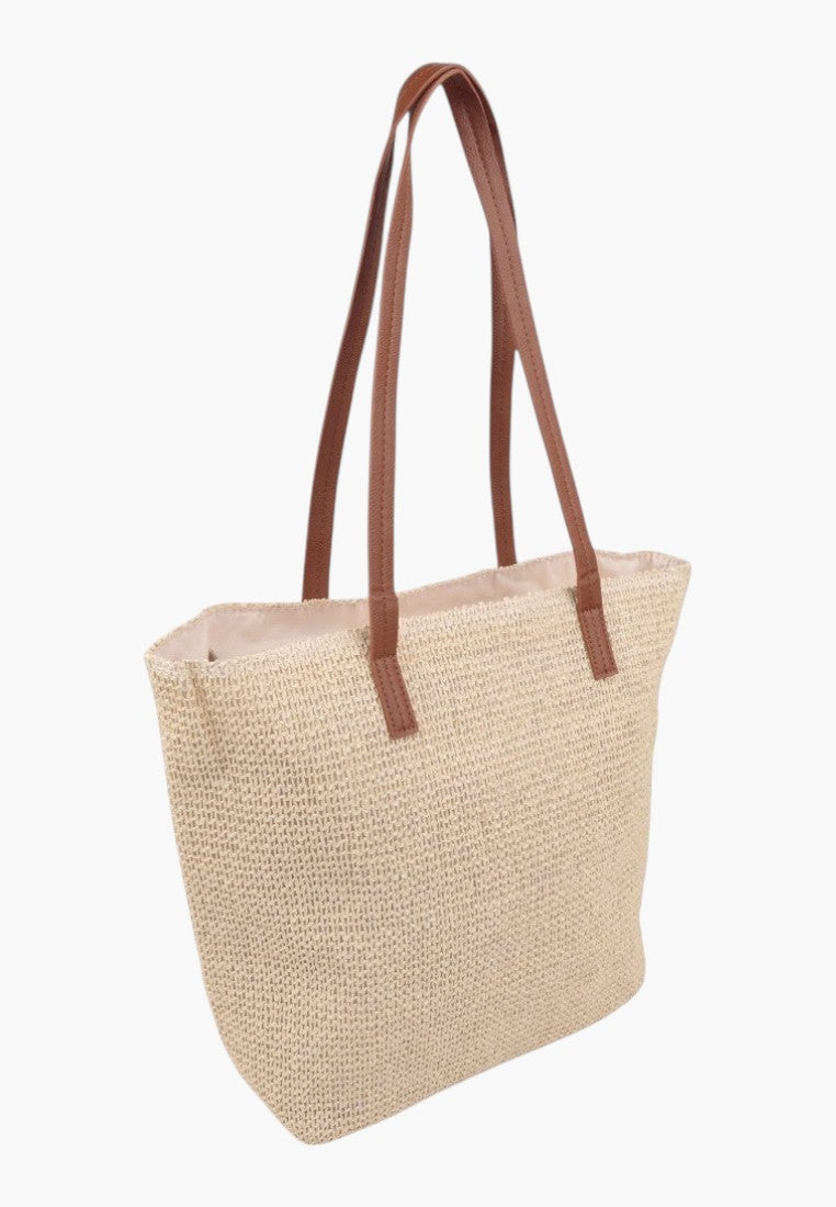 Z boku beżowej torebki damskiej shopper z długimi uchwytami na białym tle