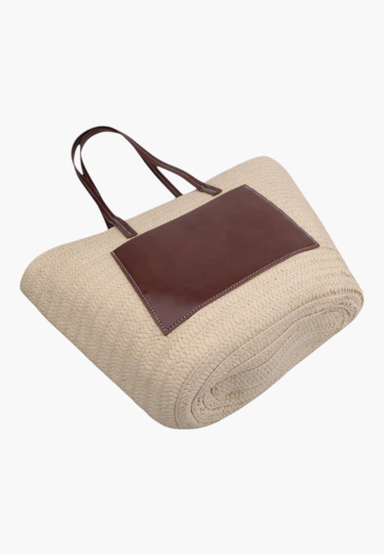 Side view of the beżowa torebka shopper z długimi paskami i zaokrąglonym kształtem.