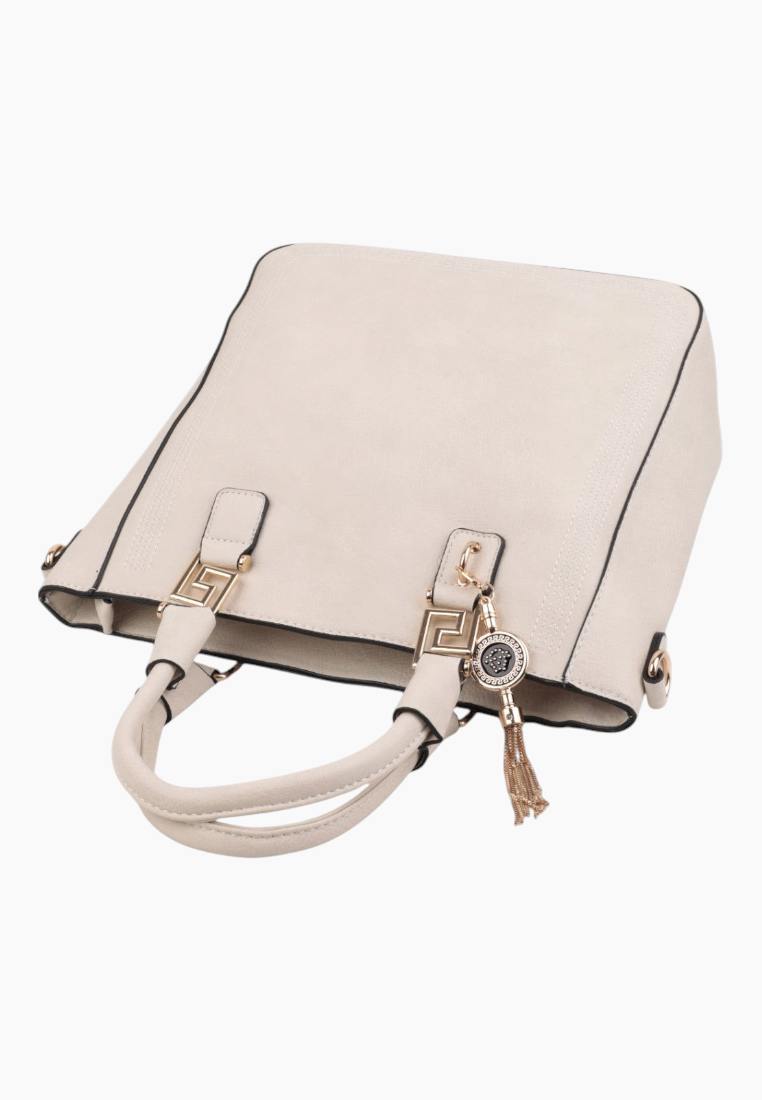 Detail close-up of cream handbag showing zipper closure and tassel detail.