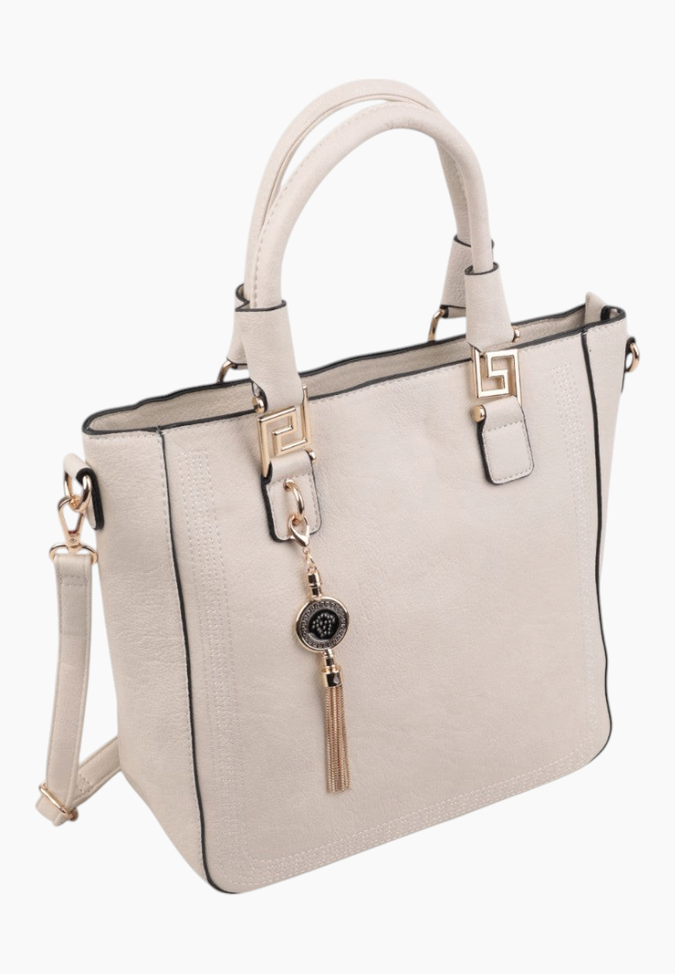 Side view of a cream handbag featuring a zipper closure and tassel charm.