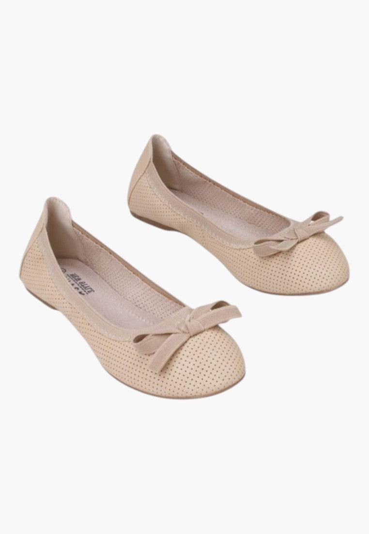 Lifestyle shot of beige ballet flats with a bow detail on a white background