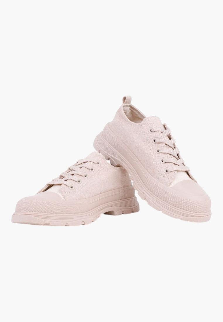 Side view of beige lace-up sneakers with a simple design on a white background