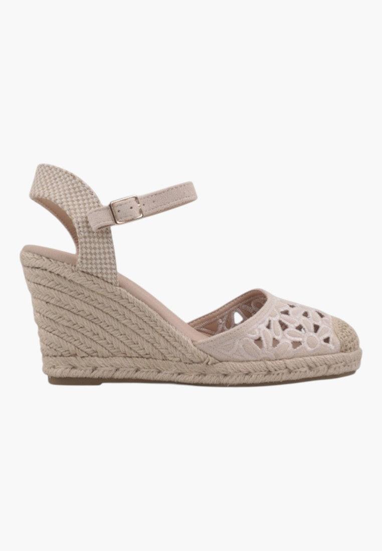 Close-up detail of beige wedge sandals showcasing woven design and textured sole.