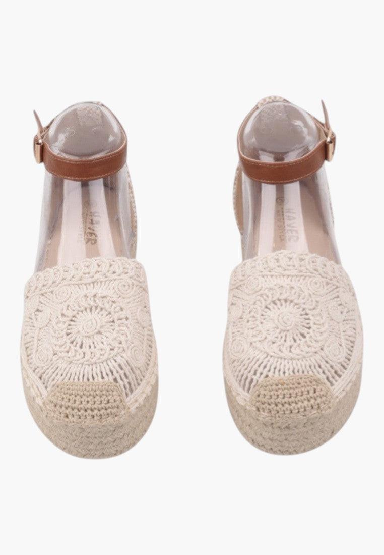 Front view of beige sandals featuring ankle strap and textured design.