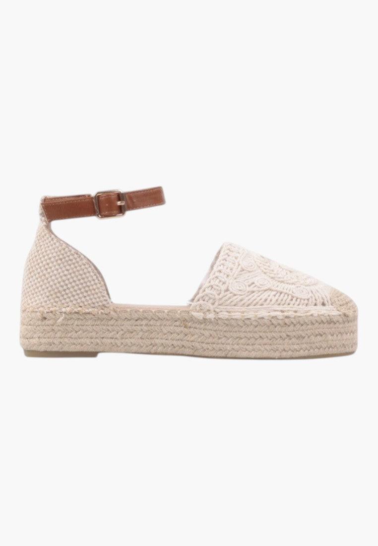 Side view of beige sandals with platform sole and ankle strap.