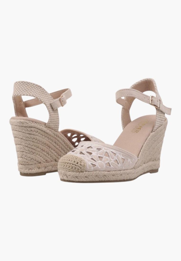 Side view of beige wedge sandals with ankle strap and woven design.