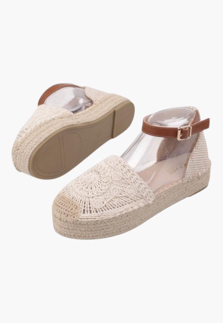 Side view of beige sandals with textured upper and ankle strap.