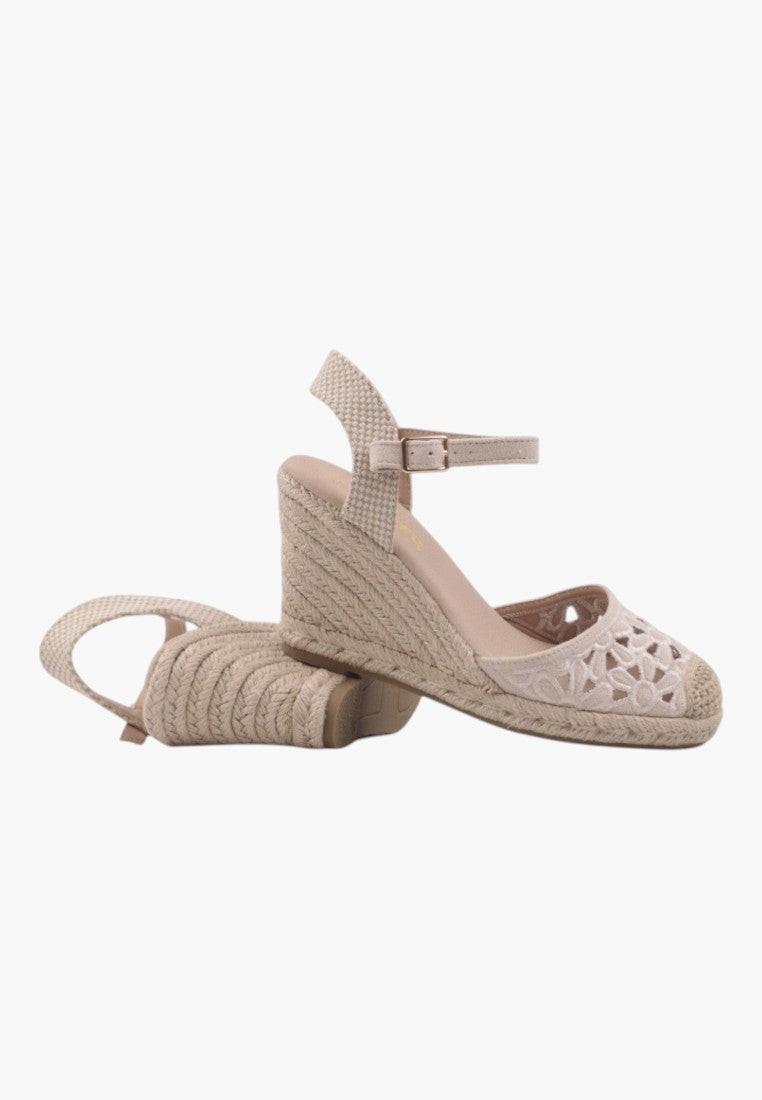 Side view of beige wedge sandals with ankle strap and closed toe.