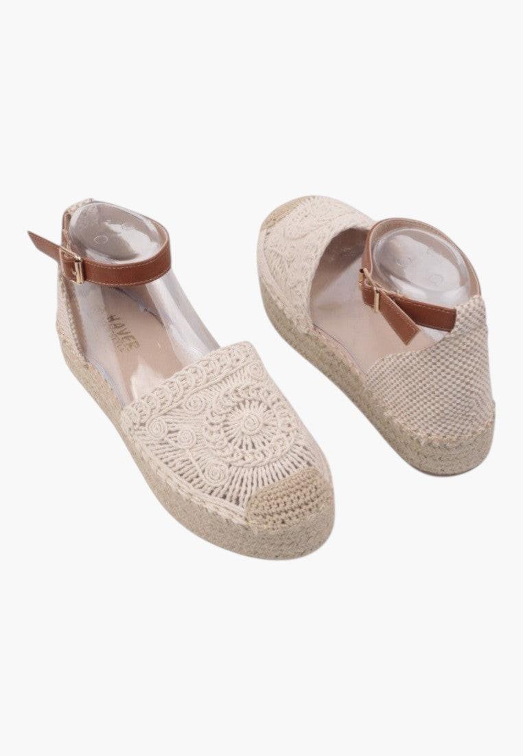 Side view of beige slip-on sandals featuring ankle strap.