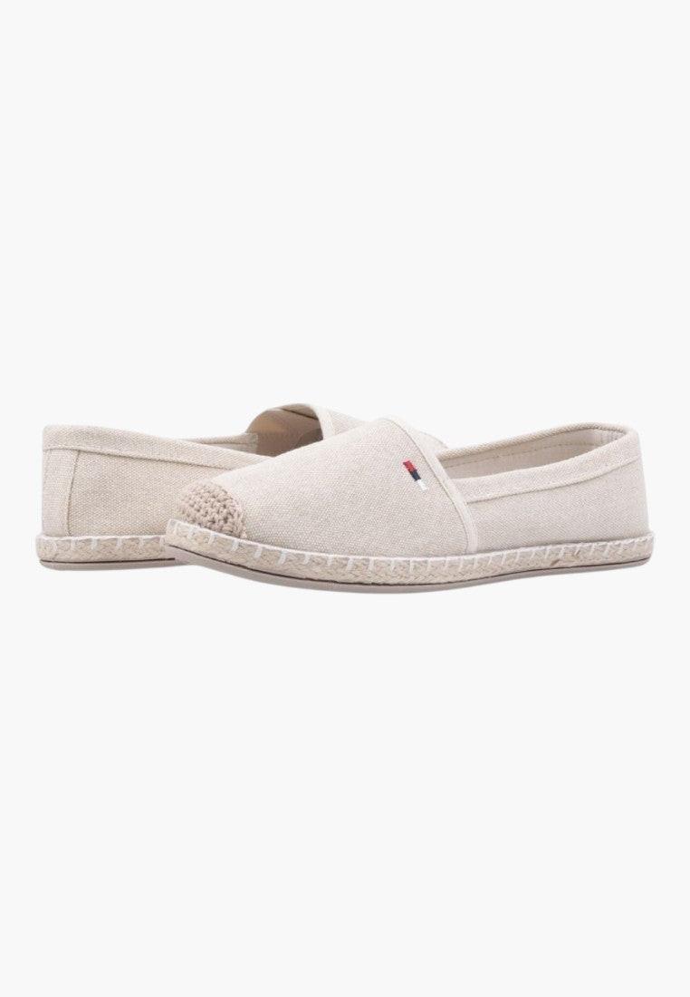 Close-up detail of beige slip-on shoes with rubber sole on a white background