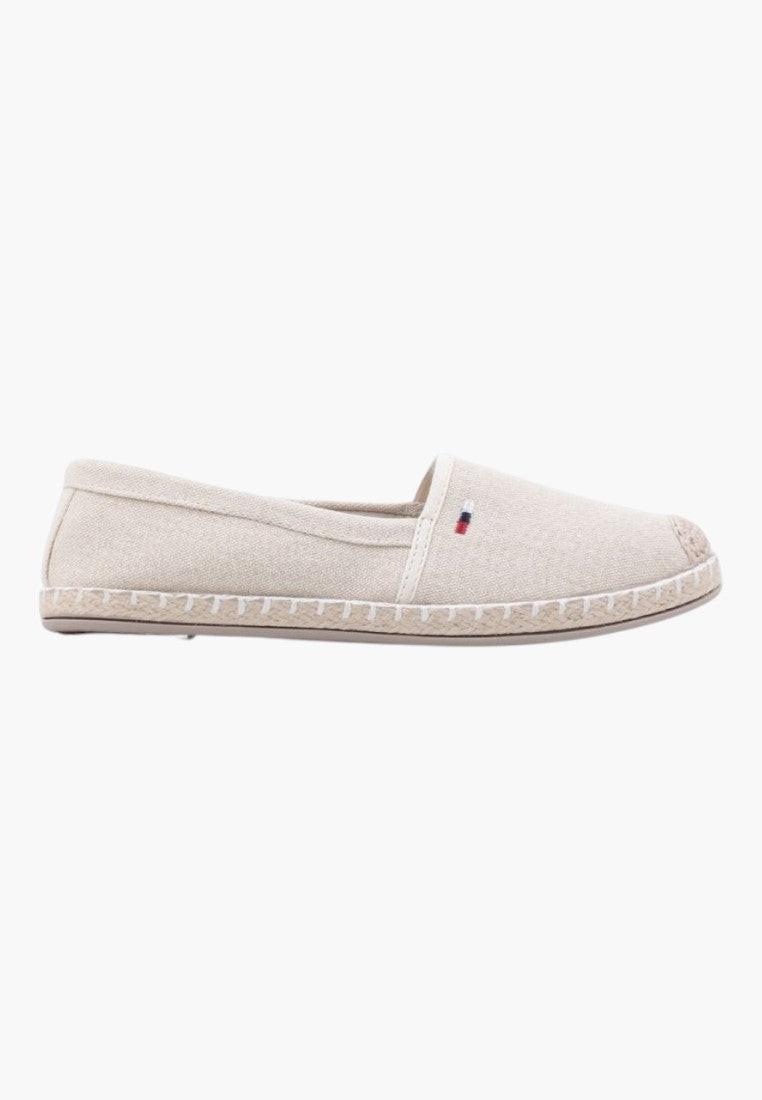 Side view of beige slip-on shoes showcasing logo detail on a white background