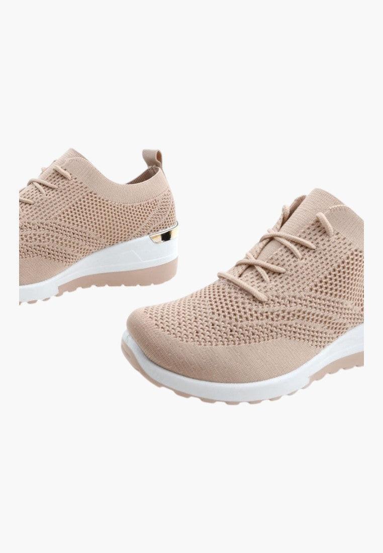 Stylowe beżowe sneakersy damskie w użyciu na białym tle