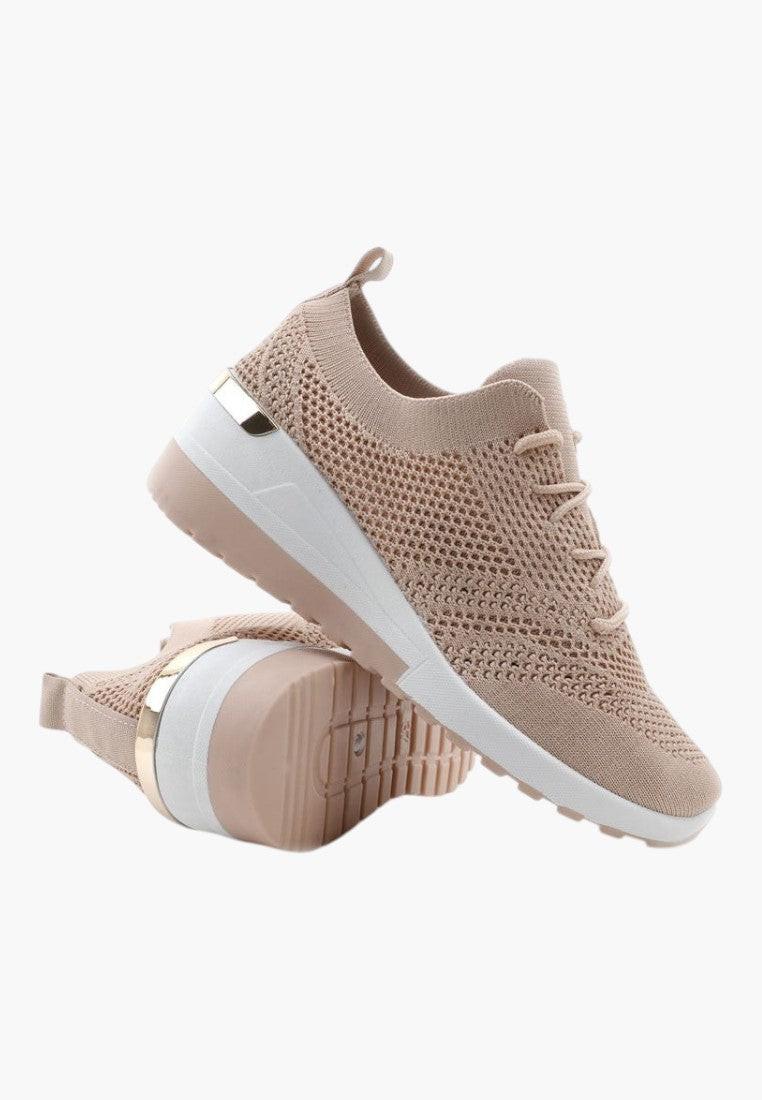Boczne ujęcie beżowych sportowych sneakersów damskich na białym tle