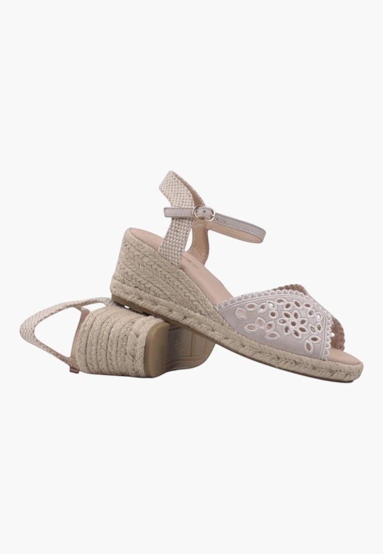Close-up detail of beige wedge sandals showcasing woven texture on a white background