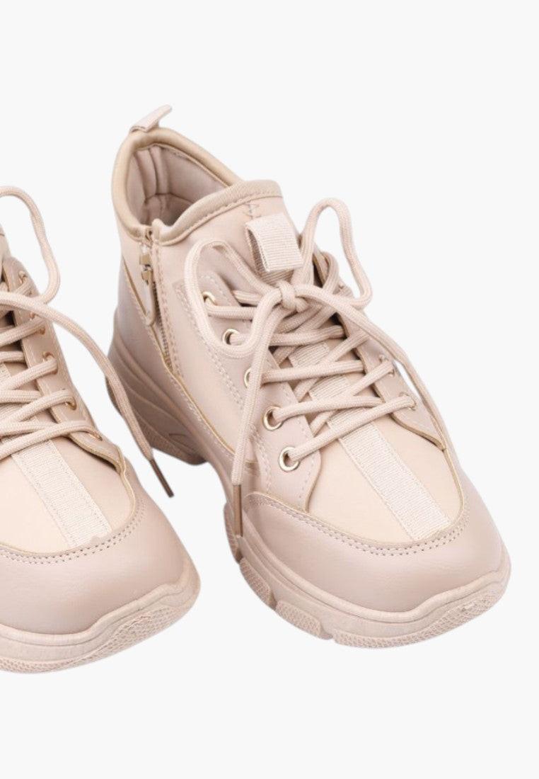 Detail view of beige sneakers with lace-up closure and padded collar.