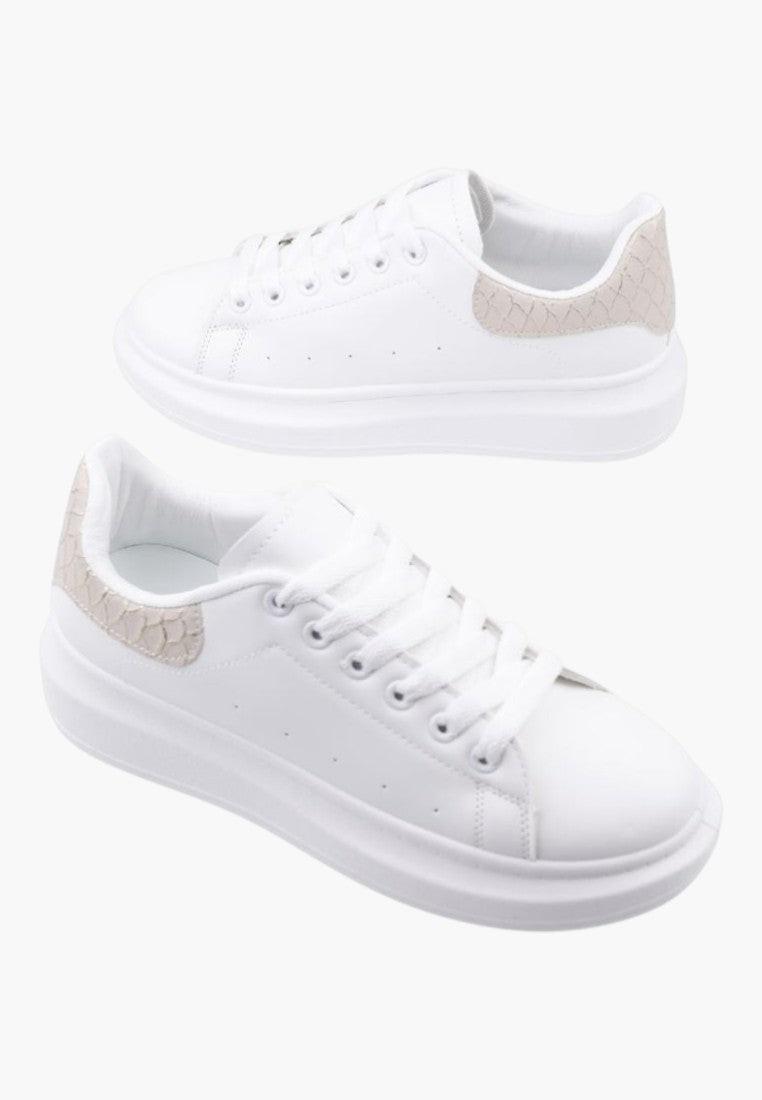 Zbliżenie na białe sneakersy damskie z teksturowaną podeszwą i sznurowaniem.