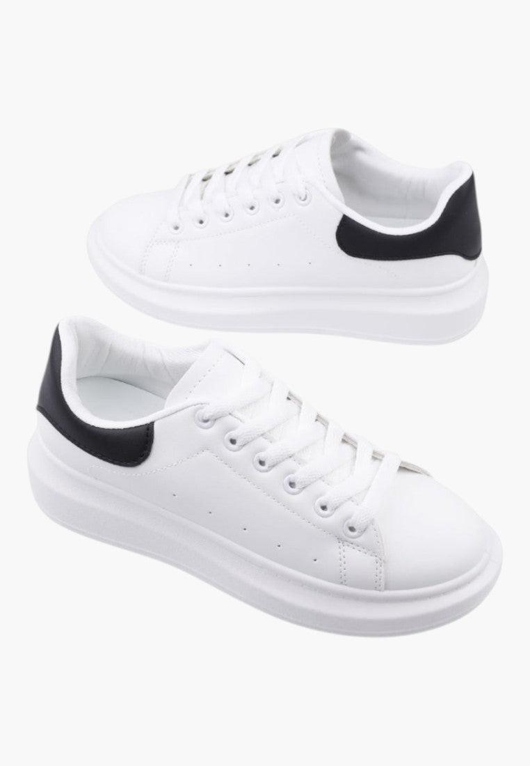 Białe sneakersy damskie w stylu casual, widok lifestyle z czarnym detalem.