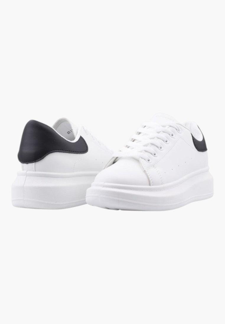 Białe sneakersy damskie w stylu casual, widok lifestyle z czarnym detalem.