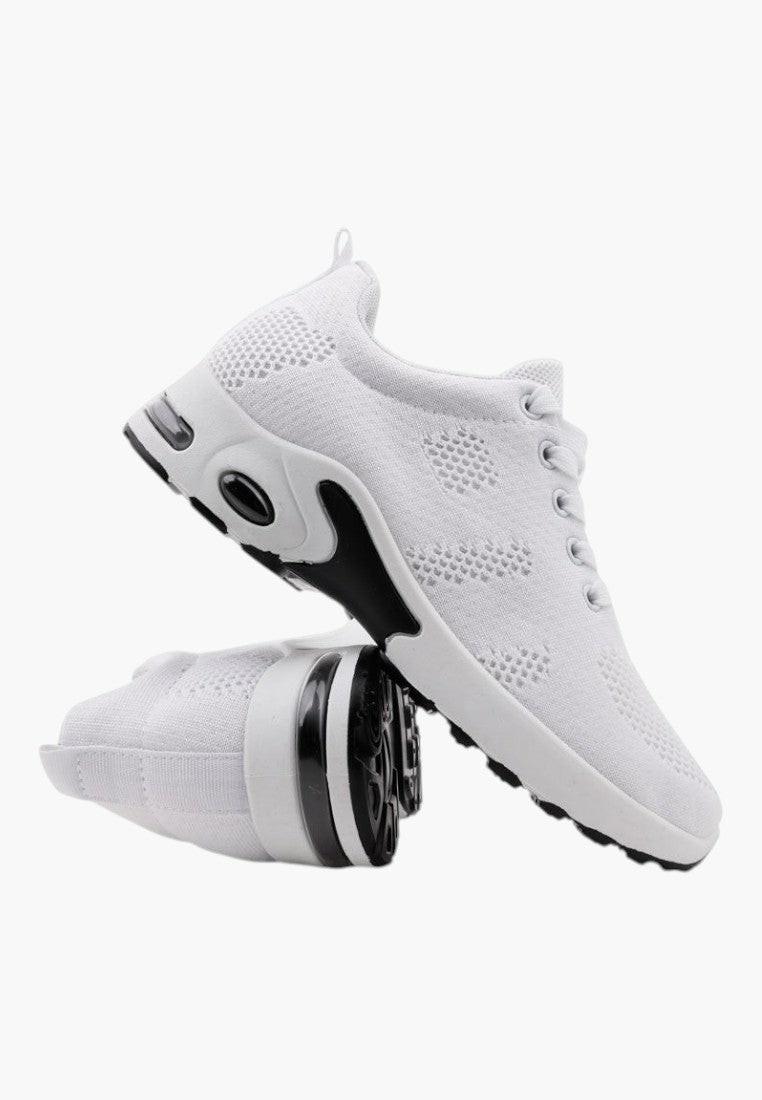 Zbliżenie na białe sneakersy damskie z siateczkowym wierzchem i czarnymi akcentami.