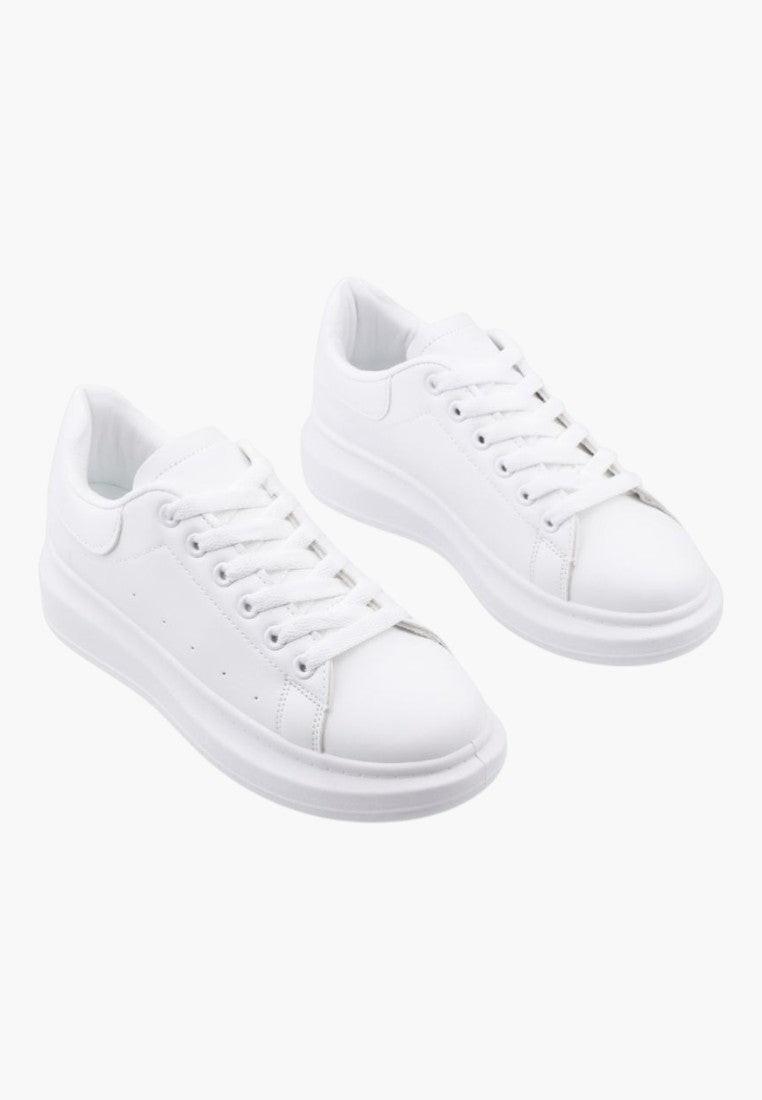 Zbliżenie na teksturowaną cholewkę białych sneakersów.