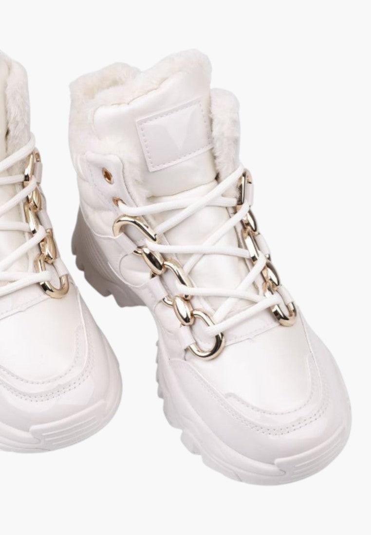 Białe sneakersy z złotymi sznurówkami, widok z bliska.
