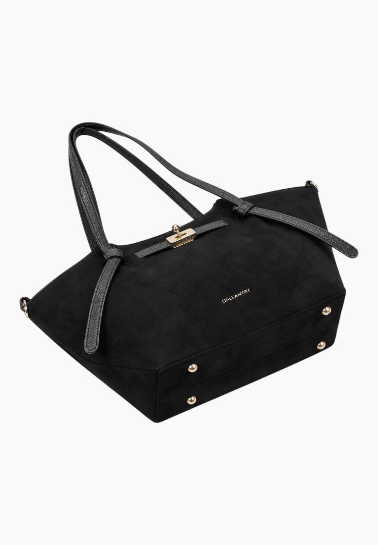 Side view of the black suede handbag with two handles and gold hardware.