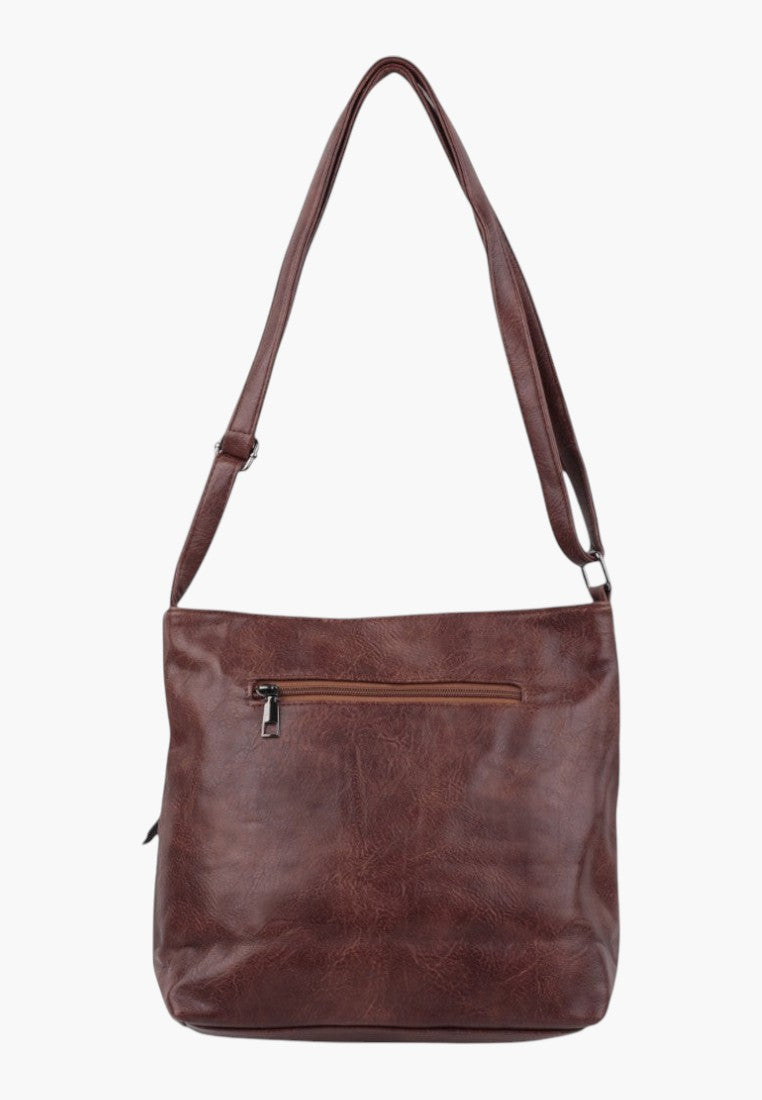 Side view of brown faux leather crossbody bag with soft texture and side pocket.