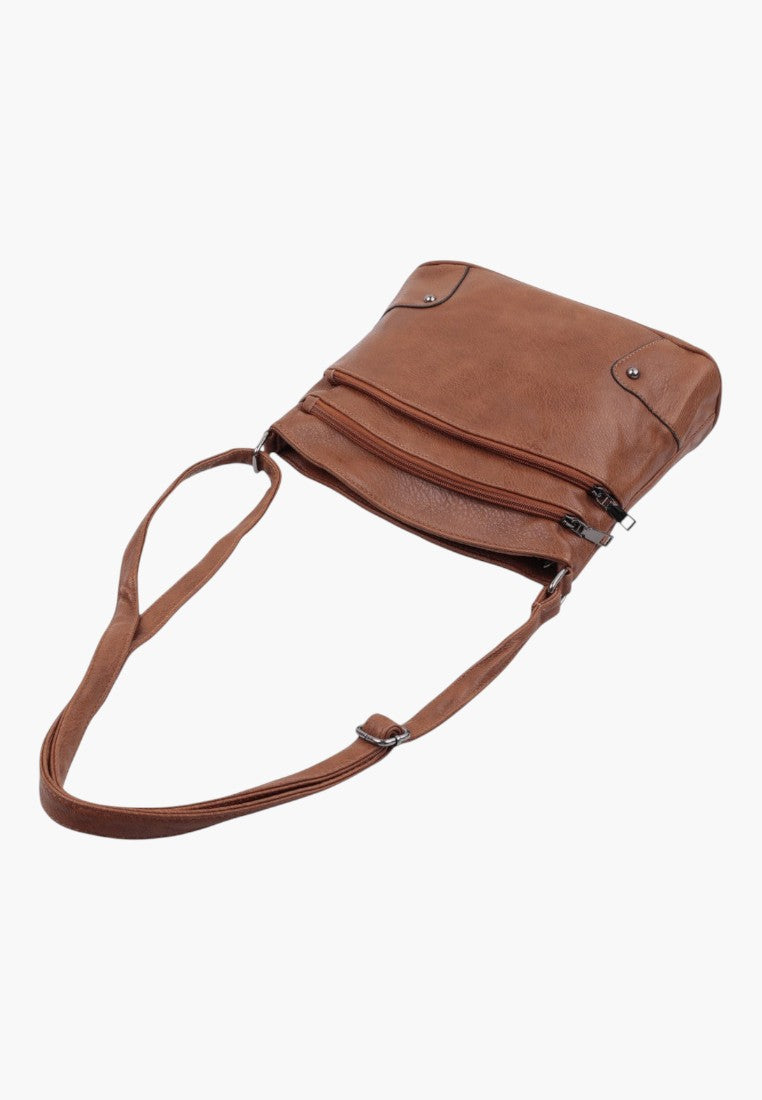 Side view of the brązowa torebka crossbody z regulowanym paskiem i płaskim dnem.