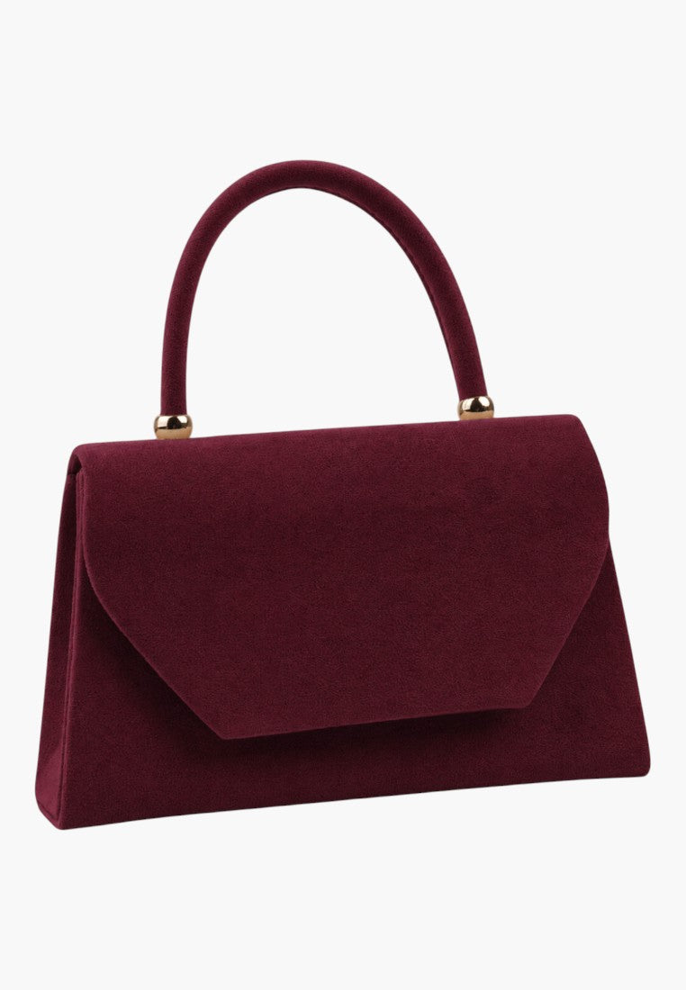 Front view of a burgundy handbag with a flap closure on a white background