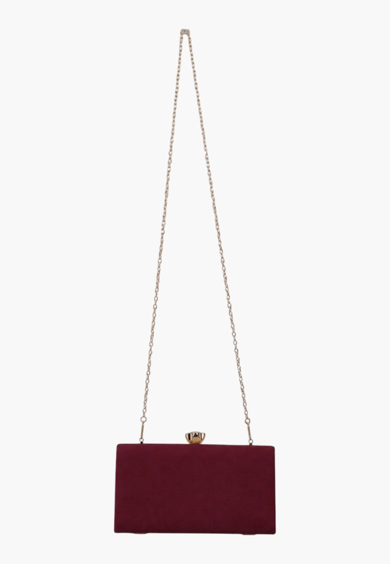 Lifestyle view of a burgundy handbag with a chain strap and clasp closure on a white background