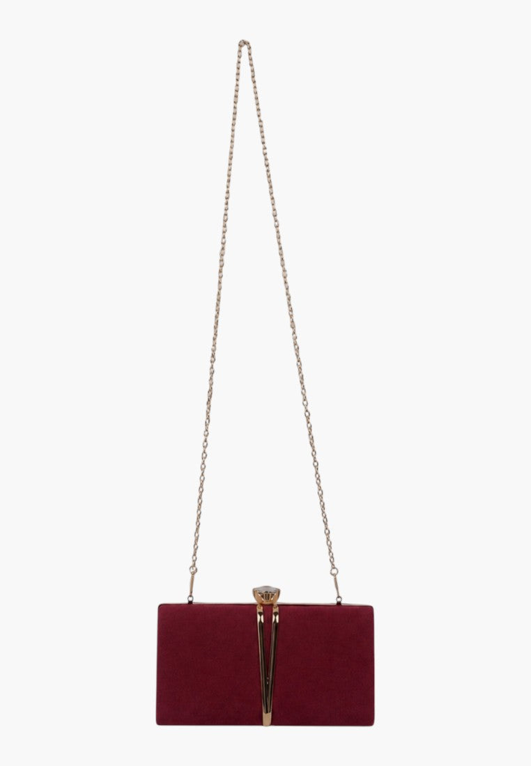 Lifestyle shot of a burgundy handbag featuring a chain strap and clasp closure on a white background