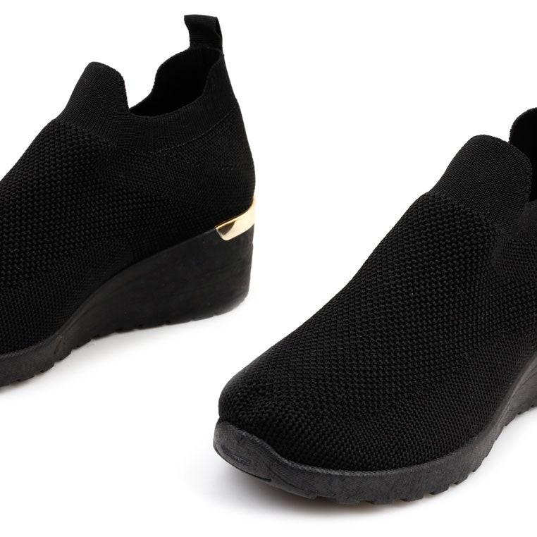Stylizacja czarnych sneakersów damskich na koturnie w codziennym otoczeniu.