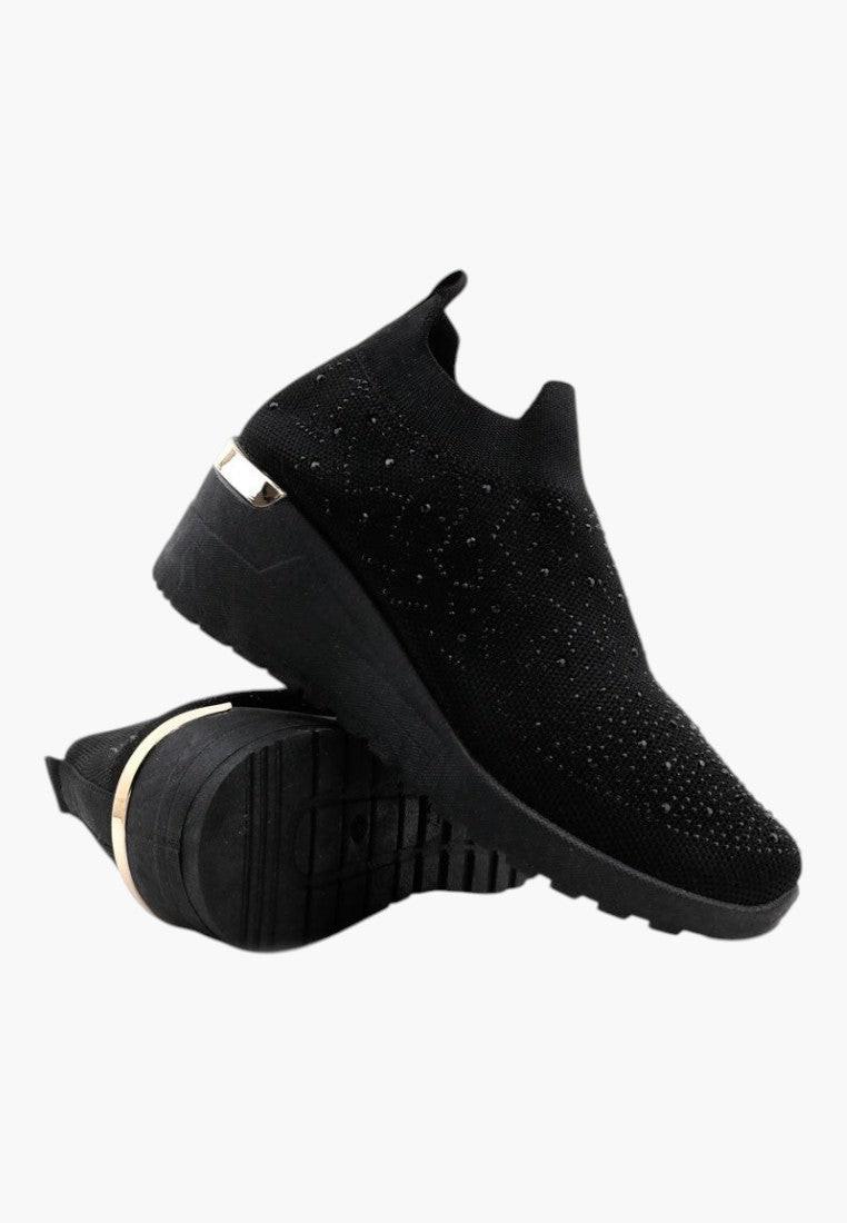 Zbliżenie na teksturowany materiał czarnych sneakersów damskich na koturnie.