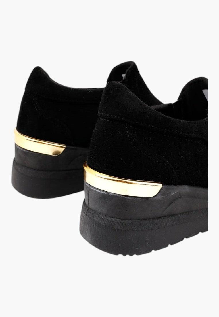 Zbliżenie na czarne sneakersy damskie na koturnie z teksturowaną powierzchnią.